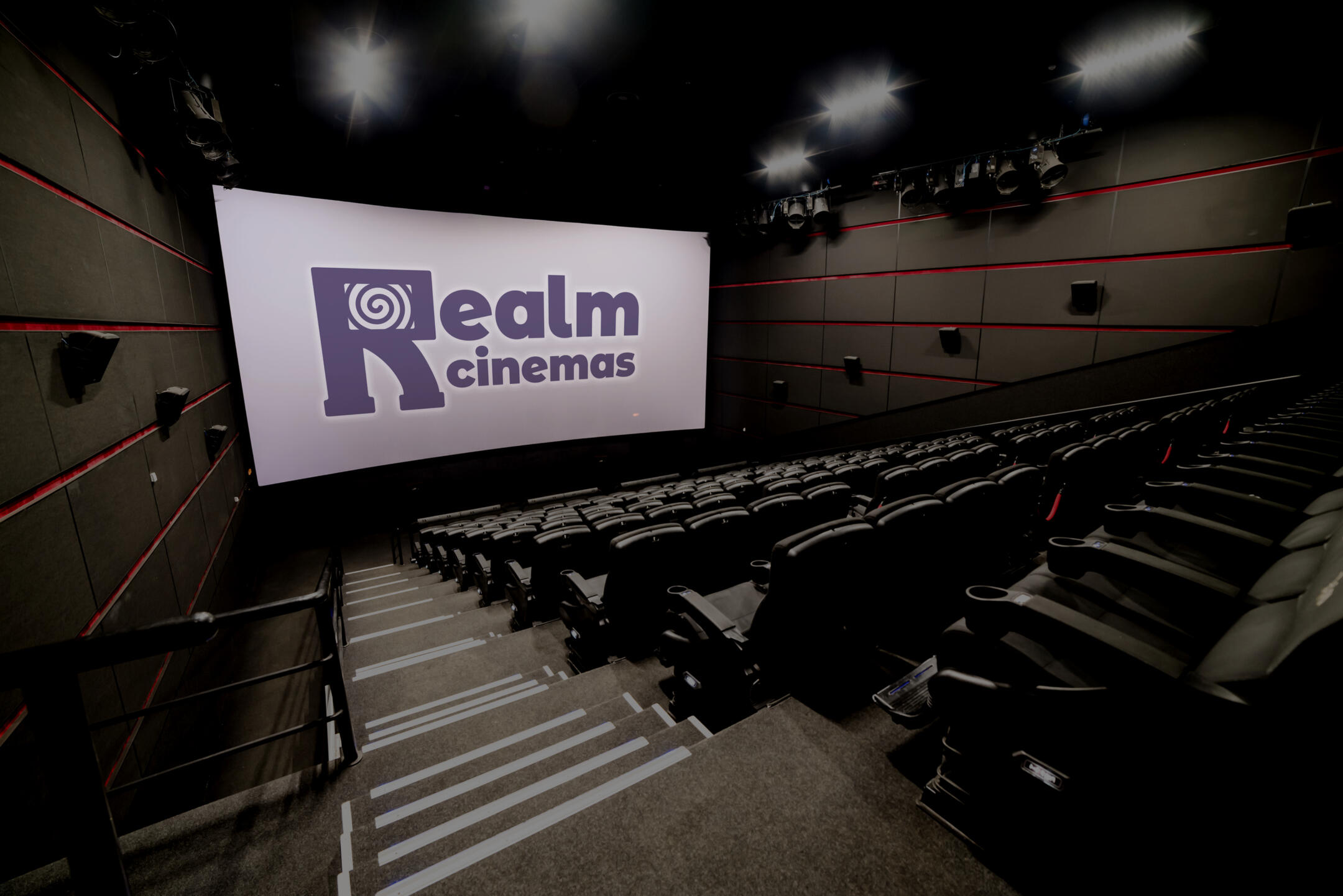 A mockup of a movie theatre with a purple Realm Cinemas logo on the screen.